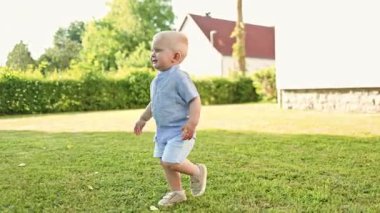 Toddler running on green grass. Active children's recreation. Smiling boy in shorts running and playing, having fun in the backyard on a sunny hot summer day. White boy playing hide and seek