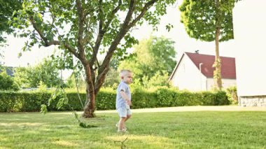 Funny little boy playing on the playground in the summer. Toddler resting after playing in the park. Happy childhood. Child on a walk in the park in the summer.