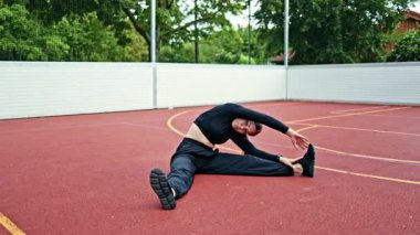 Sokaktaki spor sahasında karın kası egzersizi yapan genç bir kadın. Şehir parkında spor yapan bir kadın. Eşofmanlı ve tişörtlü kadın..