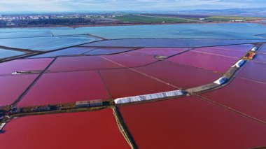 Manzara, günbatımının yumuşak parıltısı altında parlak kırmızı ve mavi renkleri yansıtan geniş tuz düzlüklerine sahiptir..
