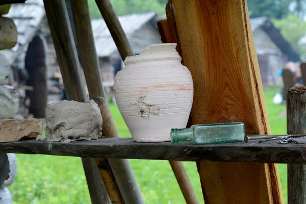 Skadade lera potten och glas flaska på trähylla. — Stockfoto