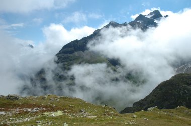 Çayır taşlar ve dağ Sustenpass yakın bulutlar arasında