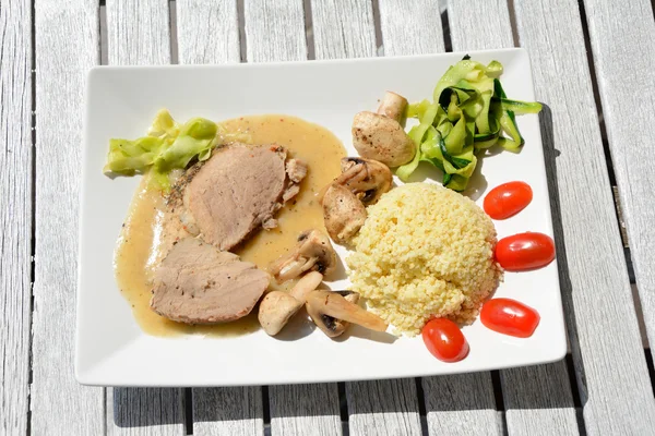 Gebackene Schweinelende, Hirsebrei, Pilze und Gemüse. — Stockfoto