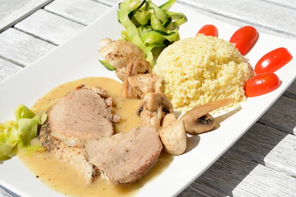 Gebackene Schweinelende, Hirsebrei, Pilze und Gemüse. — Stockfoto