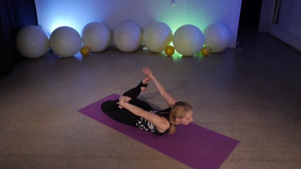 Dhanurasana.Une femme flexible qui fait du yoga dans une salle de fitness. — Video