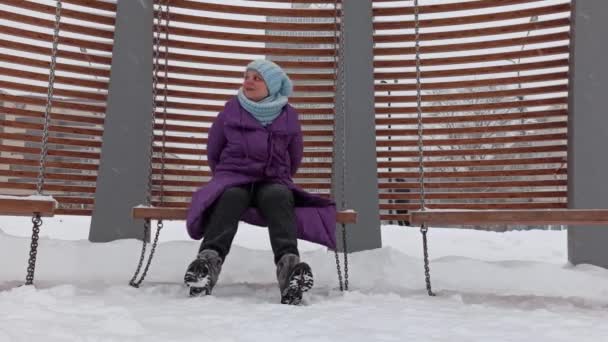 Χαμογελαστή γυναίκα ταλαντεύεται σε μια κούνια το χειμώνα. — Αρχείο Βίντεο