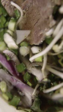 Pho bo. Vietnamlı pho bo çorbasına yakın çekim. Yemek çubukları bir parça sığır eti alır. Dikey video. Dikey. 