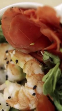 Karides ve kiraz domatesli Poke yakın çekim. Çubuklar bir parça karides alır. Yeşiller ve siyah susam. Dikey video. Dikey.