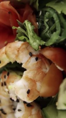 Karides ve kiraz domatesli Poke yakın çekim. Yeşiller ve siyah susam. Dikey video. Dikey.