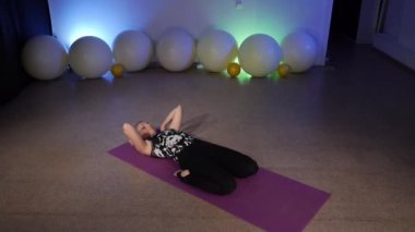 Janu Sirsasana. Tepeden tırnağa ileri eğil. Krounchasana. Heron Pozu. Esnek, orta yaşlı bir sarışın fitness kulübünde yoga yapıyor. Paspasın üstünde Asya yogası yapıyor..
