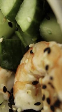 Karides ve salatalıklı poke yakın çekim. Yeşiller ve siyah susam. Dikey video. Dikey.