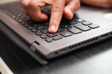 Bir parmak gri bir dizüstü bilgisayarın klavyesindeki tuşa basar. Görüntüyü kapat