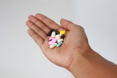 Farklı renklerde ilaçların çeşitli çeşitleri açık bir avuç içinde nazikçe tutuluyor. Vuruldu.