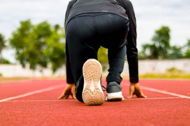 Sporcu bir koşu pistinin başlangıç çizgisinde çömelmiş, yarışa hazırlanıyordu..