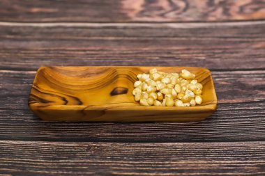 Dokunulmamış patlamış mısır çekirdekleri doğal ahşap bir kapta, ahşap bir arka planda dizilmiş..