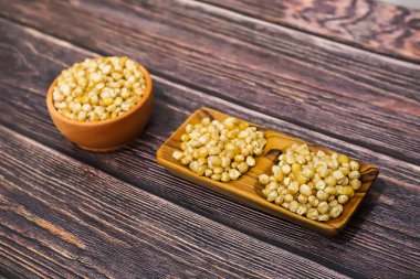 Pişmemiş mısır taneleri küçük ahşap kaselerde sunulur koyu, ahşap bir yüzeyde..