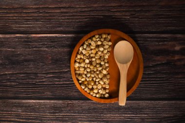 Kurumuş mısır taneleriyle dolu ahşap bir kase, ahşap bir ahşap yüzeye karşı dizilmiş..