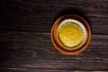 Tek bir altın hamur işi, muhtemelen bir kurabiye ya da küçük bir pasta, tahtadan bir yüzey üzerinde kağıt bir çizgide..