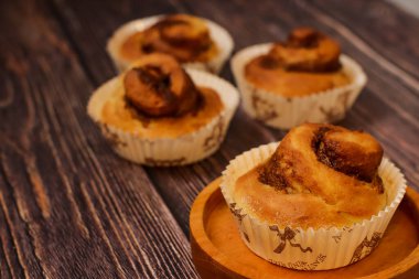 Lezzetli fırınlanmış tarçınlı kek kırsal ahşap bir yüzey üzerinde sunulur. Kahvaltı ve tatlı için mükemmeldir..