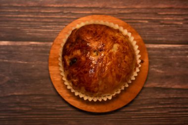 Tek bir altın fırınlanmış hamur işi ahşap bir yüzeye oturmuş, tadını çıkarmaya hazır..