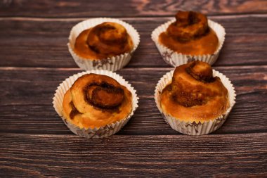 Kırsal ahşap bir yüzeye dizilmiş kağıt kaplamalı taze pişmiş tarçın ruloları..