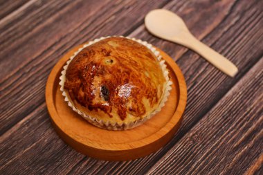 Ahşap bir kaşıkla ahşap bir tabakta servis edilen lezzetli altın kahverengimsi hamur işi, ahşap bir arka planda..