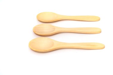 Üç basit, doğal ahşap kaşık, temiz beyaz bir arkaplanda, organik dokularını sergiliyor..