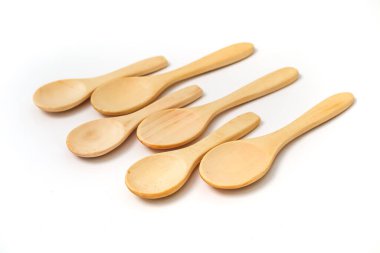 Beş küçük tahta kaşıktan oluşan bir kolleksiyon. Temiz beyaz bir arkaplanda dizilmiş, doğal dokuyu sergiliyor..