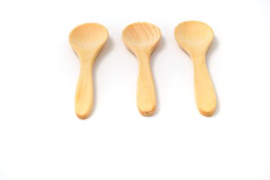 Üç doğal tahta kaşık pürüzsüz bir şekilde temiz beyaz bir yüzeye yerleştirilir..