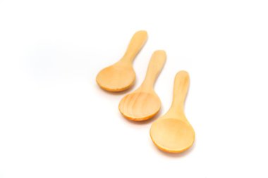 Temiz beyaz bir arkaplanda çapraz dizilmiş üç küçük tahta kaşık..