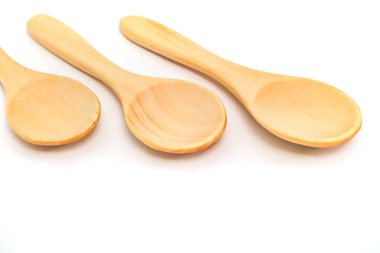 Temiz beyaz bir arka planda sıralanmış üç farklı boyutta üç doğal tahta kaşık..