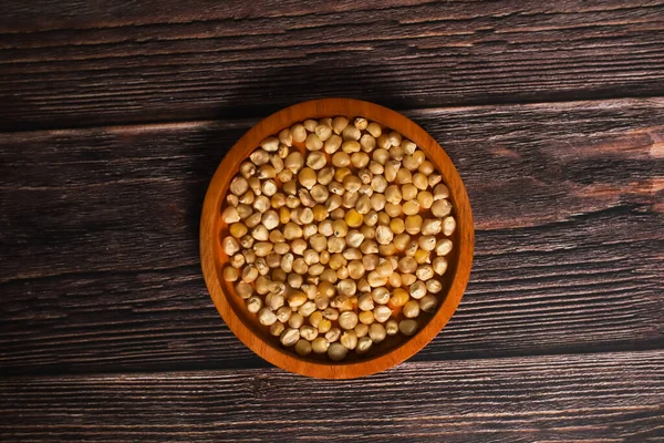 Kurumuş mısır çekirdekleri ile dolup taşan kırsal bir ahşap kase, koyu, ahşap bir yüzeyde duruyor..