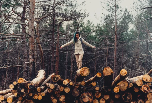 Girl walking on stack of tree trunk — Stock Photo, Image