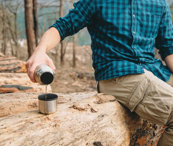 Man pouring tea in forest 