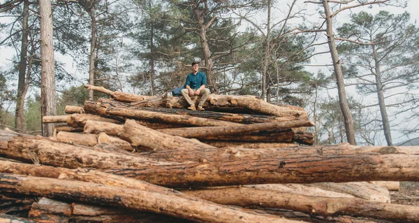 Viajero descansando en la pila de troncos de árboles — Foto de Stock