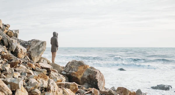 Mujer parada en la costa de piedra — Foto de Stock