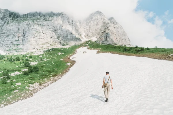 Homem caminhando na neve nas montanhas — Fotografia de Stock