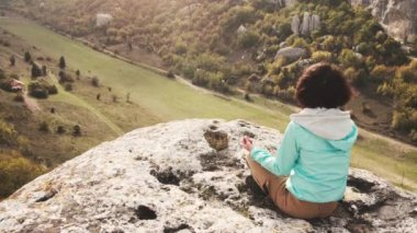 Gezgin genç kadın nilüfer çiçeği pozu vererek meditasyon yapıyor ve yazın dağın tepesinde dinleniyor..