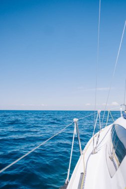 Güneşli bir günde mavi denizde yelken açmak. Güverteden pruvaya bir manzara. İnsan yok. Resmin sol kısmında kopyalama alanı.