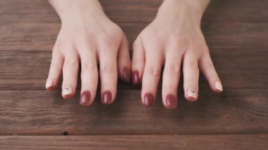 Ahşap bir arka planda profesyonel manikür ve jöle ojeli genç kadın elleri. Güzellik salonu.