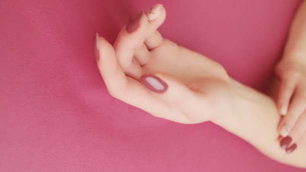 美丽的女人的手与时髦的指甲红色和米黄色的粉红色背景 垂直录像 — 图库视频影像