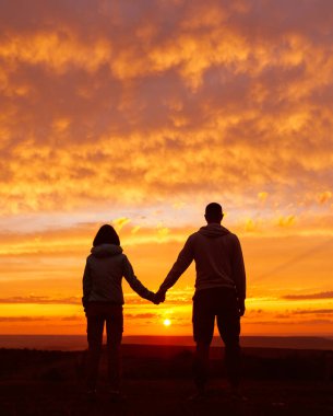 Günbatımına ve doğaya hayran genç bir çiftin silueti..