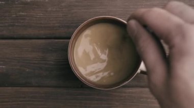 Adamın eli, kahveyi tahta bir masada kaşıkla karıştırıyor..