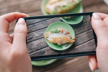 Bir kadının kahvaltı için fotoğraf çekmesi ya da cep telefonuyla video çekmesi..