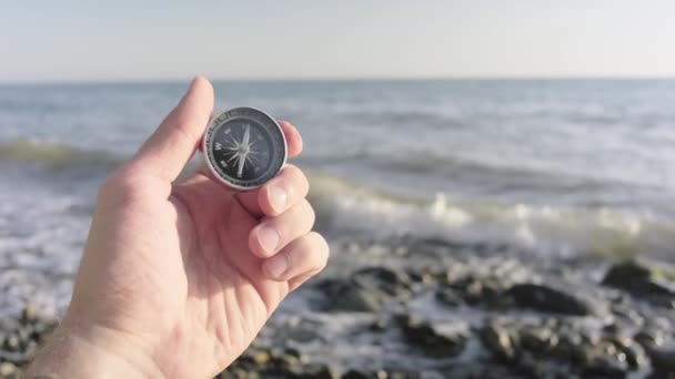 Tourist compass on a male palm in the background sea waves. — Stock Video