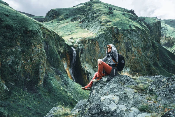 Traveler man sits on a stone in the mountains — Stock Photo, Image