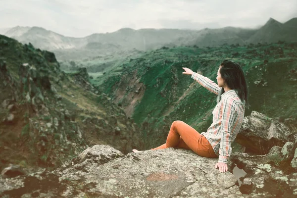 Turista mujer en las montañas apunta con su mano en la distancia. —  Fotos de Stock