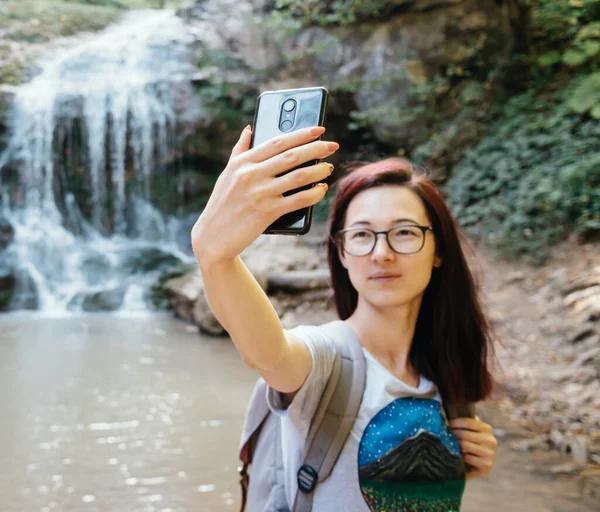 Giovane donna con uno zaino fa foto selfie. — Foto Stock