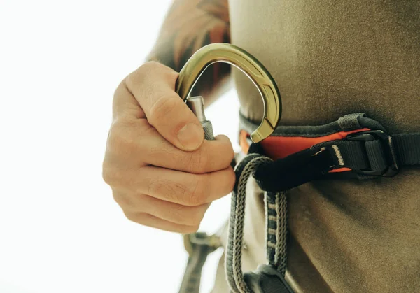 Homem alpinista segura um mosquetão em sua mão. — Fotografia de Stock