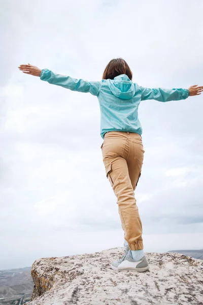 Jonge vrouw staat op de top van een berg. — Stockfoto